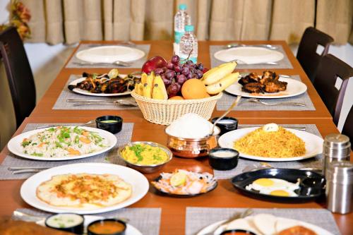 a wooden table with plates of food on it at Villa Grand Hotel Near Kempegowda International Airport in Bengaluru