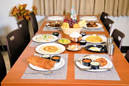 a long table with plates of food on it at Villa Grand Hotel Near Kempegowda International Airport in Bengaluru
