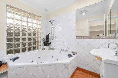 Un baño blanco con bañera y lavabo. en Kurrajong Village Delight, en Kurrajong