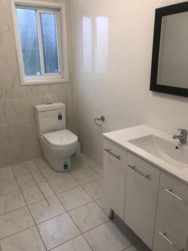 a white bathroom with a toilet and a sink at Branxton Baybrook Apartment in Branxton