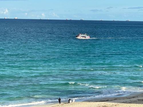 a boat in the ocean with people on the beach at Alzohour Family condo with panoramic sea view in Alexandria