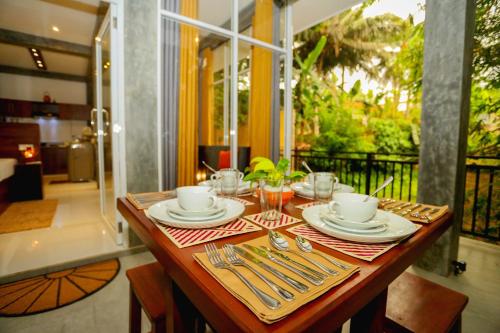 a wooden table with plates and silverware on it at Villa Sanni 18 in Hikkaduwa