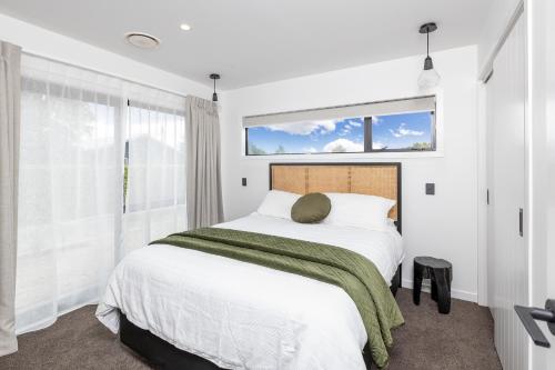 a white bedroom with a large bed and a window at The Green House - Luxury Eco Escape in Martinborough 