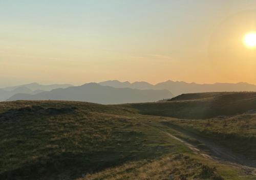 a sun setting over a field with mountains in the background at FLOR de MONTANHAS - 4PERS - Appart vacances in Arette