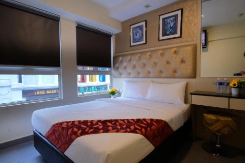 ein Schlafzimmer mit einem großen Bett und zwei Fenstern in der Unterkunft Sandpiper Hotel Singapore in Singapur