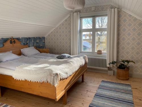 Un dormitorio con una cama grande y una ventana en Charmig stuga på bondgård en Norrfjärden