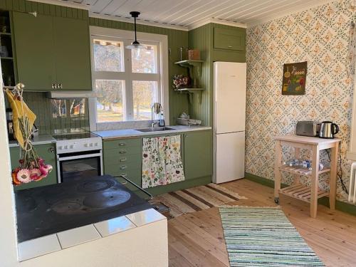 a kitchen with green cabinets and a stove top oven at Charmig stuga på bondgård in Norrfjärden