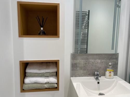 uma casa de banho com lavatório, espelho e toalhas em The Den em Stuartfield