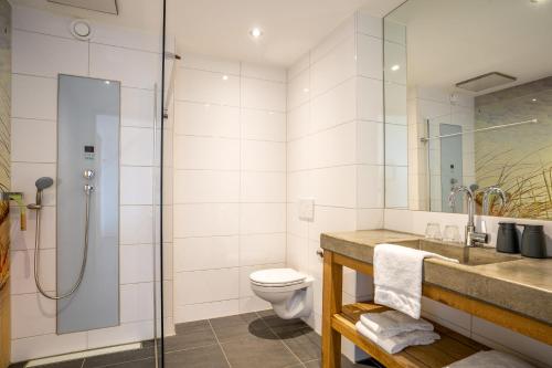 a bathroom with a shower and a sink and a toilet at Nieuw Leven Texel in Den Burg
