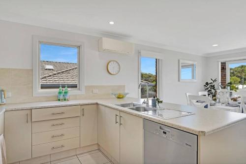 une cuisine blanche avec un évier et une fenêtre dans l'établissement Coastal Vibes- Ultimate Beachside lifestyle, à Port Macquarie
