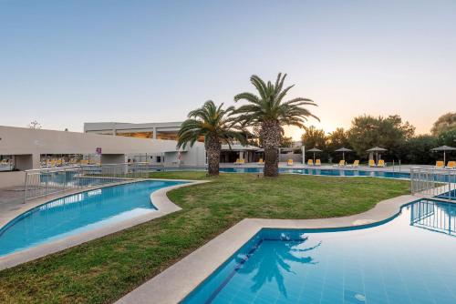 a view of the pool at a resort with palm trees at E-GEO Easy Living Resort in Marmari