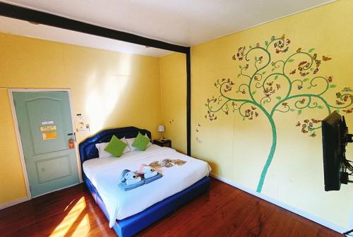a bedroom with a bed with a tree painted on the wall at Aen Guy Boutique Hotel in Sukhothai