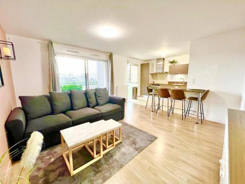 a living room with a blue couch and a kitchen at L'atelier Chic - Wifi fibre - Parking privée - Balcon - NETFLIX in Lanester