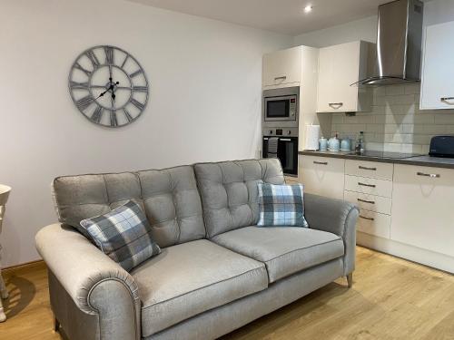 a living room with a couch and a clock on the wall at The Den in Stuartfield