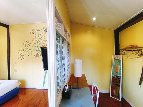 a bedroom with yellow walls and a bed and a table at Aen Guy Boutique Hotel in Sukhothai