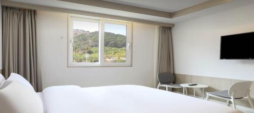 a hotel room with a bed and a window at Geoje Mongdol Beach H Avenue Hotel in Geoje 