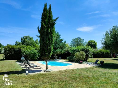 un arbre à côté d'une piscine dans une cour dans l'établissement Cottage normand chaleureux avec piscine, 