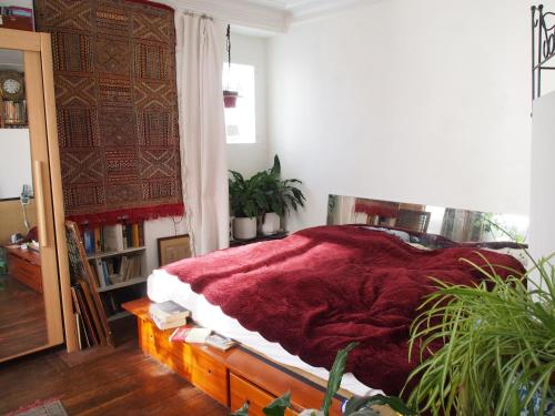 a bedroom with a bed with a red blanket on it at Very large private room with own bathroom, in Montmartre apartment in Paris
