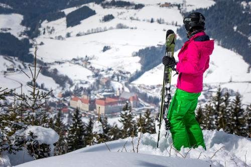 a person in a pink jacket holding skis on a mountain at Panorama Apartment Bauernhof Mandl in Murau