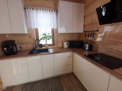 a kitchen with white cabinets and a sink and a window at Zymbiańsko Chałupa 1 z balią na wyłączność in Ząb