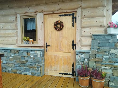 a front door of a log cabin with a stone wall at Zymbiańsko Chałupa 1 z balią na wyłączność in Ząb