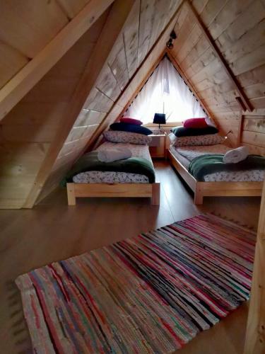 a room with four beds in a attic with a rug at Zymbiańsko Chałupa 1 z balią na wyłączność in Ząb