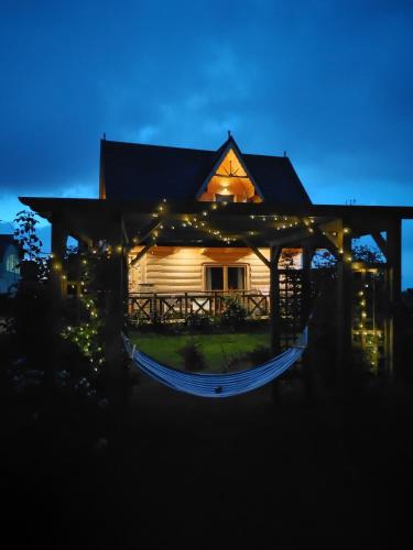 a house lit up at night with a hammock in front at Zymbiańsko Chałupa 1 z balią na wyłączność in Ząb