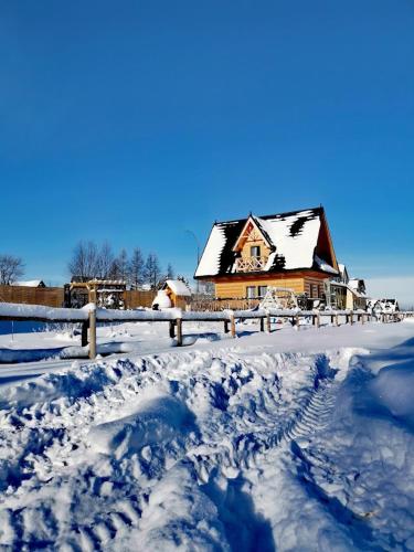 a house covered in snow next to a fence at Zymbiańsko Chałupa 1 z balią na wyłączność in Ząb