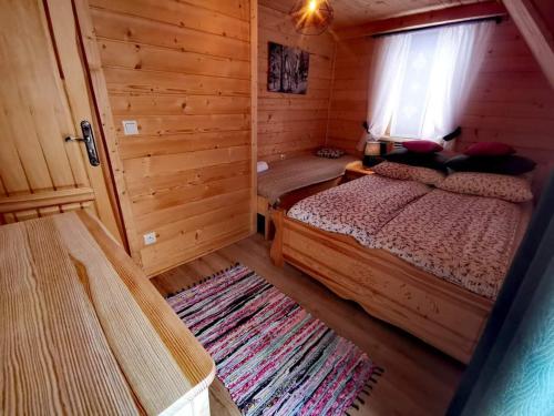 a bedroom with a bed and a window in a log cabin at Zymbiańsko Chałupa 1 z balią na wyłączność in Ząb