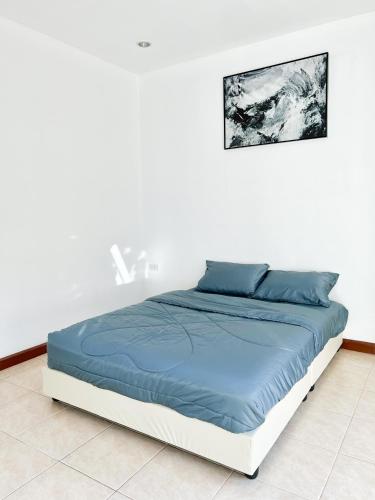 a bed in a white room with a blue blanket at Sky&Sea Cha-AM Beach in Cha Am