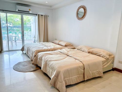 two beds in a bedroom with a mirror on the wall at Sky&Sea Cha-AM Beach in Cha Am