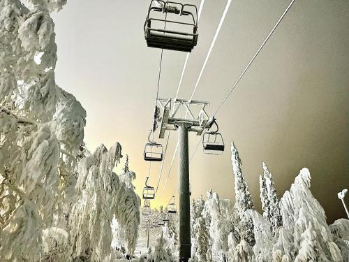 a ski lift in the snow with snow covered trees at Arctic Lodges Lapland Ski In Family Studio, Wi-Fi, National Park - Lapland Villas in Pyhätunturi