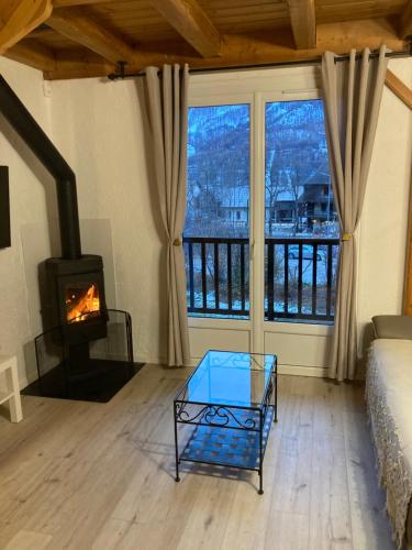 - un salon avec une cheminée, un canapé et une table en verre dans l'établissement appartement Monetier les bains, au Monêtier-les-Bains