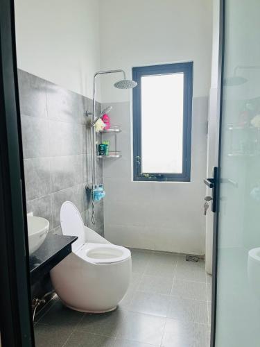 La salle de bains est pourvue de toilettes, d'un lavabo et d'une fenêtre. dans l'établissement Thông Villa, à B'su M'rac