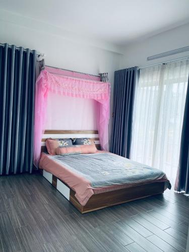un letto rosa con baldacchino rosa in una camera da letto di Thông Villa a B'su M'rac