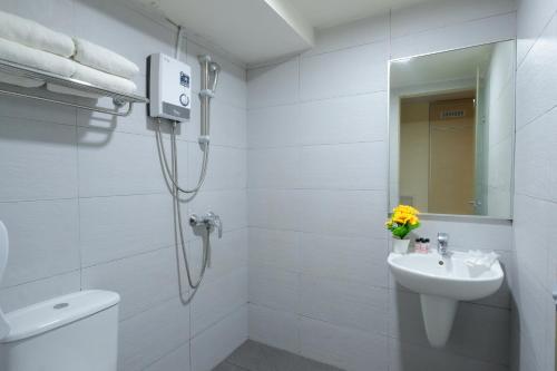 a white bathroom with a shower and a sink at Sandpiper Hotel Singapore in Singapore