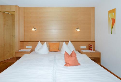 um quarto com uma grande cama branca com almofadas laranja em Fernblick Frühstückspension em Schoppernau