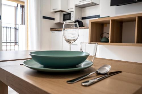 a green bowl and a glass of wine on a table at CALMA Apartments in Benidorm
