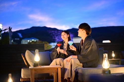 a man and a woman sitting on a couch on a patio at Urakusatsu TOU in Kusatsu