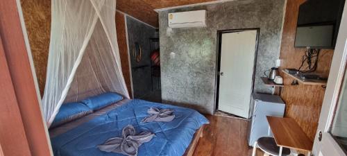 a small bedroom with a blue bed with flowers on it at Our Village Bungalows in Koh Mook