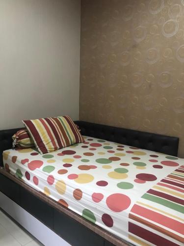 a bed with a polka dot sheet and a pillow at Private single room in Cigadung in Bandung