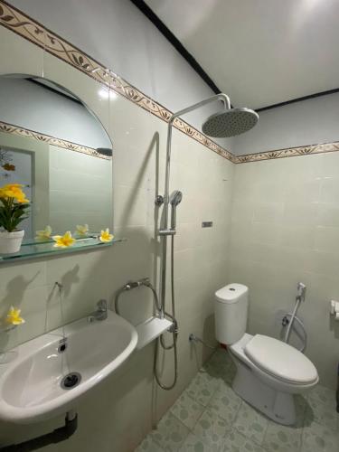 a bathroom with a sink and a toilet and a mirror at Guest House Pondok Puspa Ayu in Kuta
