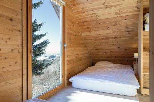 a bed in a wooden room with a large window at Kostovac Boutique Homes - House 1 in Kopaonik