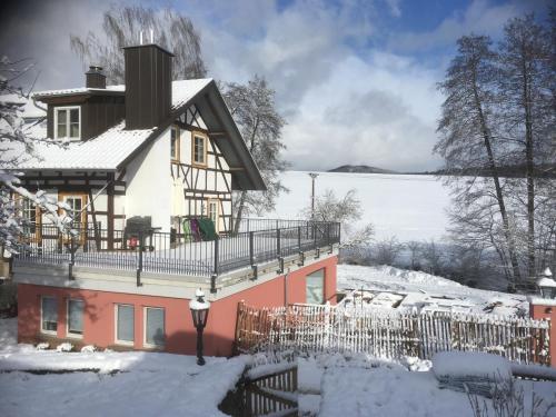 une maison avec un balcon dans la neige dans l'établissement Ferienwohnungen Grundmühle, à Nordheim vor der Rhön