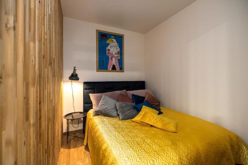 a bedroom with a bed with a yellow bedspread at Žiedų apartamentai in Klaipėda