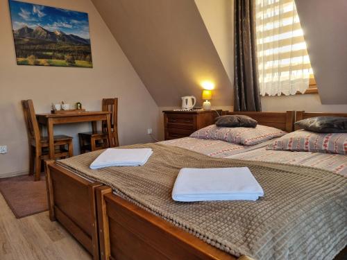 two beds in a room with a table and a table at Pokoje u Hani - sauna, balia z hydromasażem in Bukowina Tatrzańska
