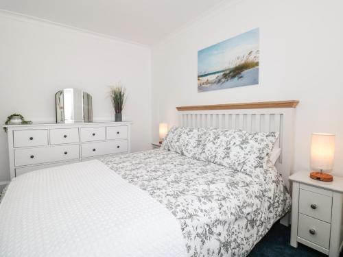 a white bedroom with a bed and two night stands at Little Honeynook in Kingsbridge