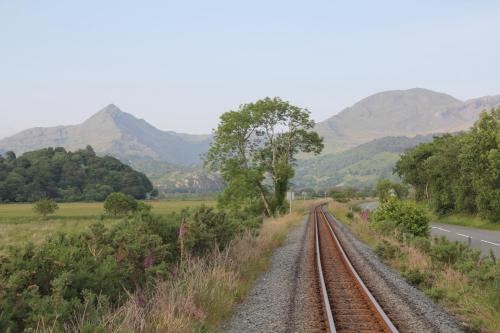 a train track next to a road with mountains at Aberdunant Hall in Porthmadog