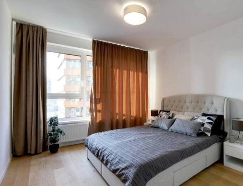 ein Schlafzimmer mit einem großen Bett und einem großen Fenster in der Unterkunft Klinger apartment in Bratislava