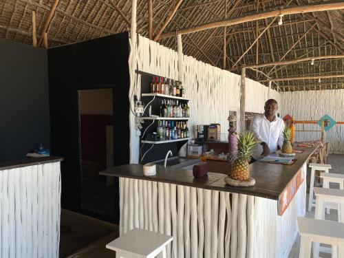 a man is standing behind a counter in a restaurant at Luwa Beach&Suits in Watamu
